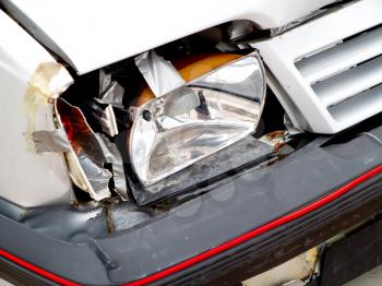 Detail of broken front headlight on white car