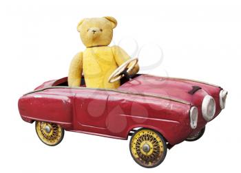 Old teddy bear in a vintage toy car isolated on white