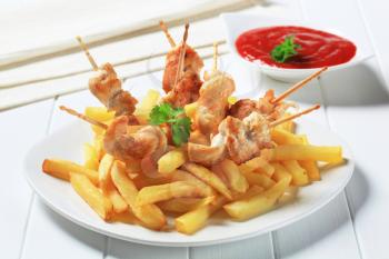 Chicken skewers with French fries and red sauce
