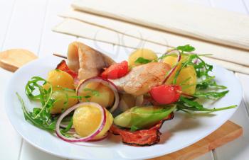 Fish skewer and potatoes with leek and arugula