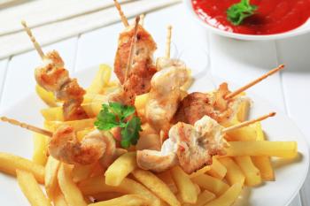 Chicken skewers with French fries and red sauce