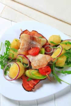 Fish skewer and potatoes with leek and arugula