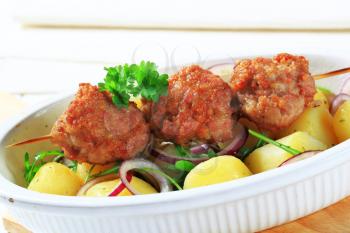 Meatballs on a wooden skewer with potatoes