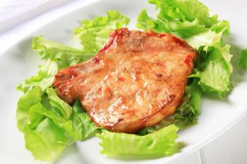 Glazed pork chop on lettuce leaves