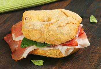 Ring-shaped bread roll (friselle) with slices of dry-cured ham