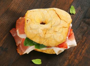 Ring-shaped bread roll (friselle) with slices of dry-cured ham