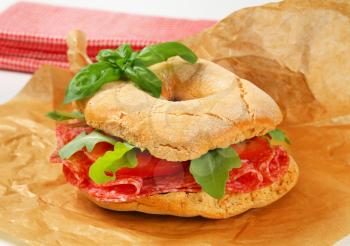 Italian bread roll with thin slices of dry salami