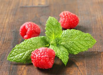 Mint leaves and raspberries on wooden background
