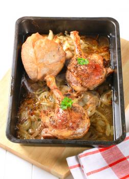 Roast duck legs with caraway and onion in a baking pan