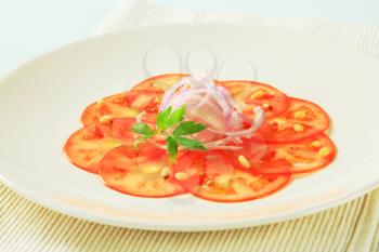 Thinly sliced tomato with onion and pine nuts
