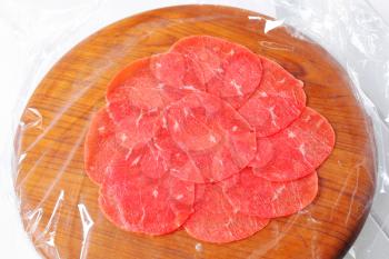 Thinly sliced raw beef on cutting board