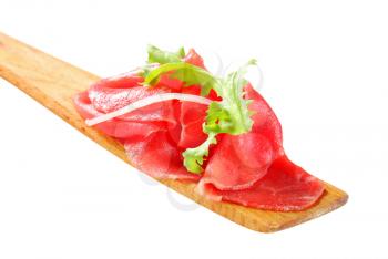 Thin slices of raw beef on wooden spatula