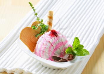Scoop of ice cream garnished with wafers and herbs