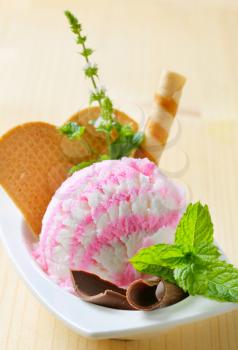 Scoop of ice cream garnished with wafers and herbs