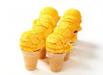Scoops of yellow ice cream in wafer cones 
