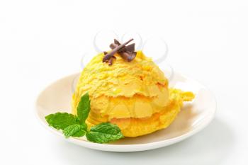 Scoop of yellow ice cream on plate
