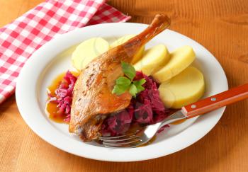 Dish of roast duck leg with potato dumplings and braised red cabbage