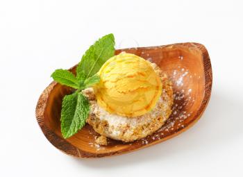 Almond cookie and scoop of ice cream served on olive wood bowl