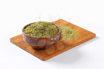 Heap of dried Marjoram leaves in a wooden bowl