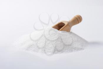 Heap of white sugar and wooden scoop