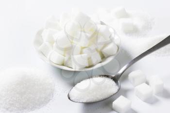 Spoonful of fine granulated sugar and pile of sugar cubes