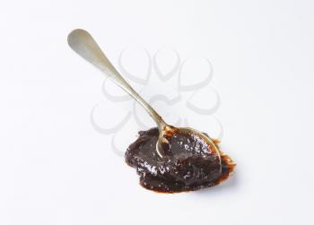 Spoon of plum jam on white background