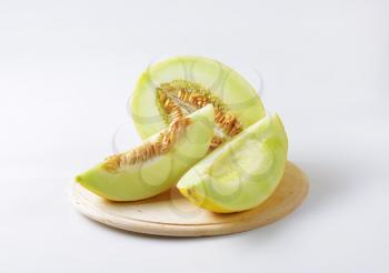 Yellow melon half and slices on cutting board