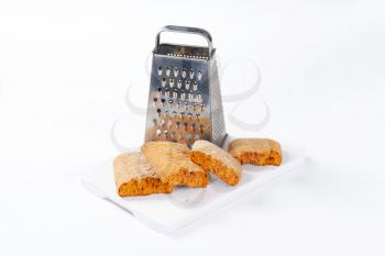Halved gingerbread biscuits and grater
