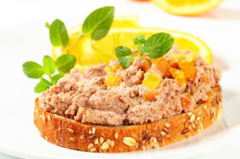 Whole grain bread with meat spread and pieces of candied orange rind