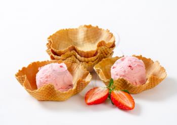 Scoops of strawberry ice cream in waffle baskets