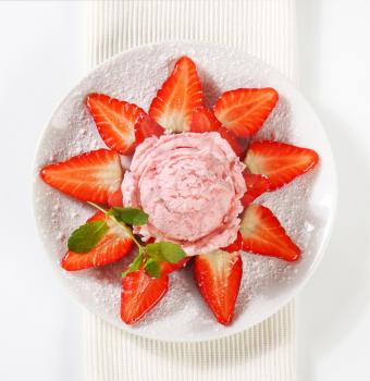 Fresh strawberries arranged around scoop of pink ice cream