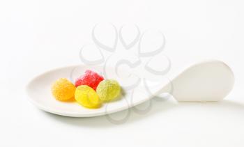 Fruit-shaped gummy candy on ceramic spoon
