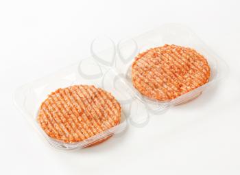 Raw burger patties in plastic packaging