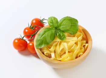 Cooked tagliatelle pasta in wooden bowl