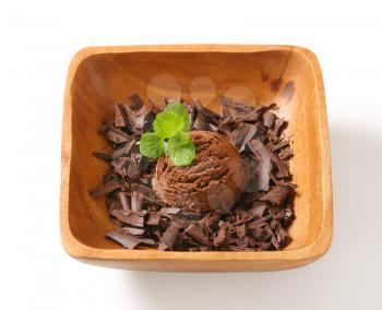 Scoop of ice cream and chocolate shavings in wooden bowl
