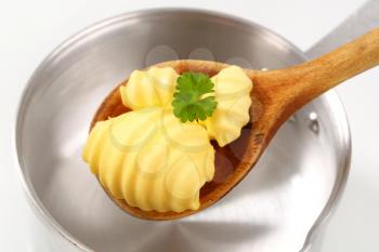 Butter curls on wooden spoon and saucepan