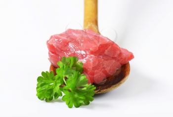 Chunk of raw beef meat on wooden spoon