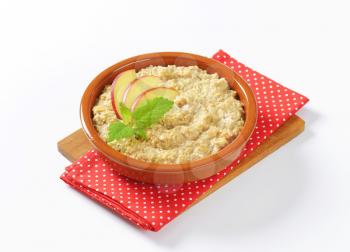 Bowl of white oats porridge with fresh apple