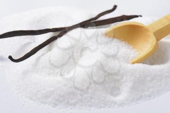 Heap of white sugar and small wooden spoon