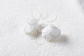 Two white sugar cubes and granulated sugar