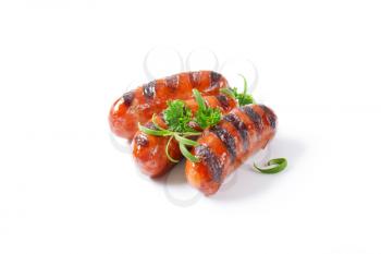 three grilled sausages on white background