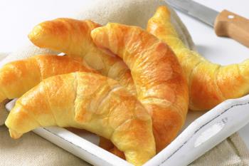Fresh butter crescent rolls (croissants) on white wooden tray