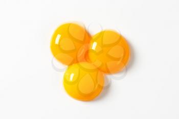 Three raw egg yolks on white background