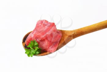 Chunk of raw beef meat on wooden spoon