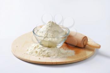 Bowl of flour and rolling pin on a wooden board