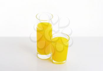 two glasses of orange juice on white background