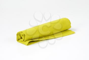 Rolled green cloth napkin on white background