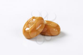 two caramel candies on white background