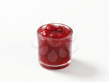 glass of strawberry jam on white background