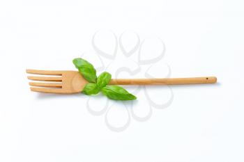 wooden fork with fresh basil on white background